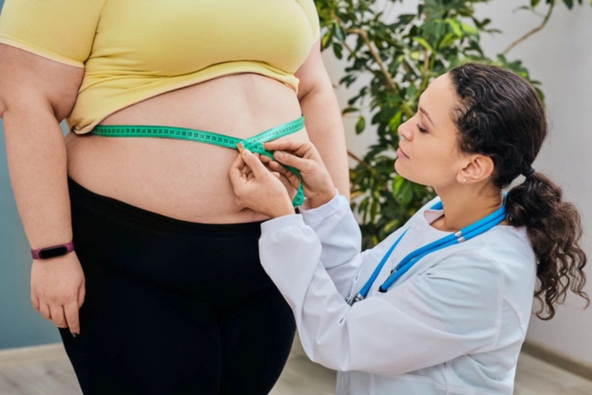 Nutricionista inspeccionando la cintura de una mujer con una cinta métrica para prescribir una dieta de adelgazamiento