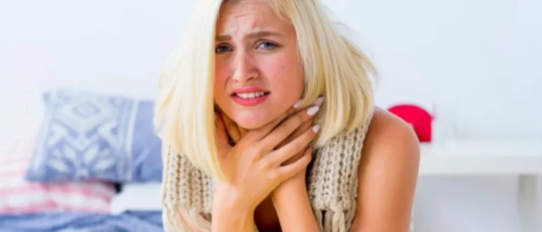 Mujer enferma sujetando su garganta.