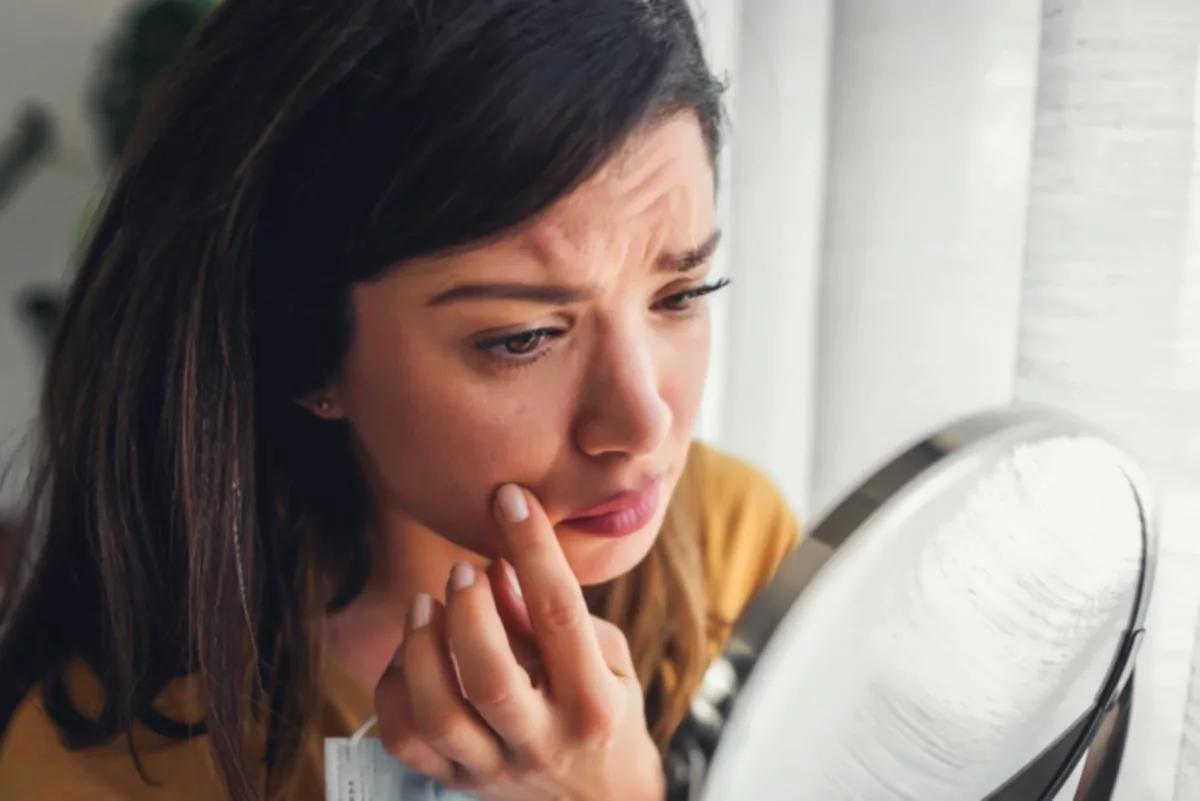 mujer preocupada mirando en el espejo cáncer de piel