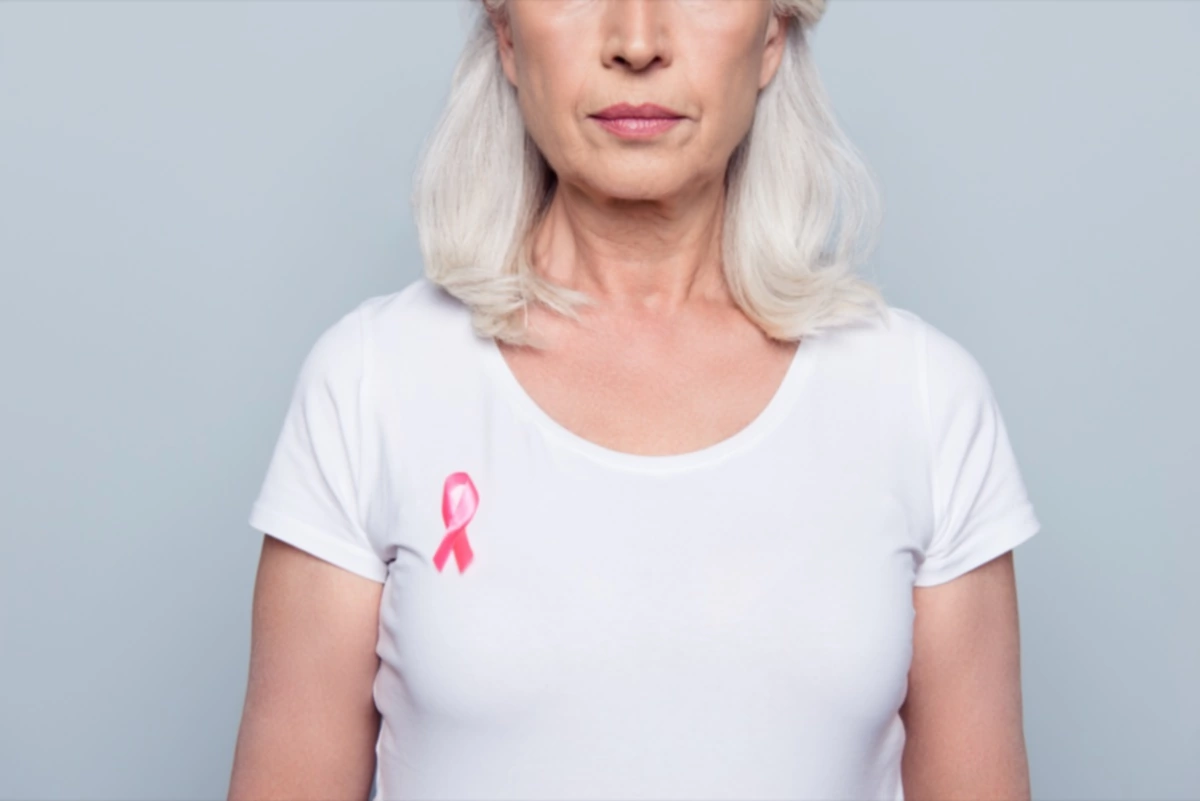 mujer con camiseta blanca y lazo rosa contra el cáncer de mama