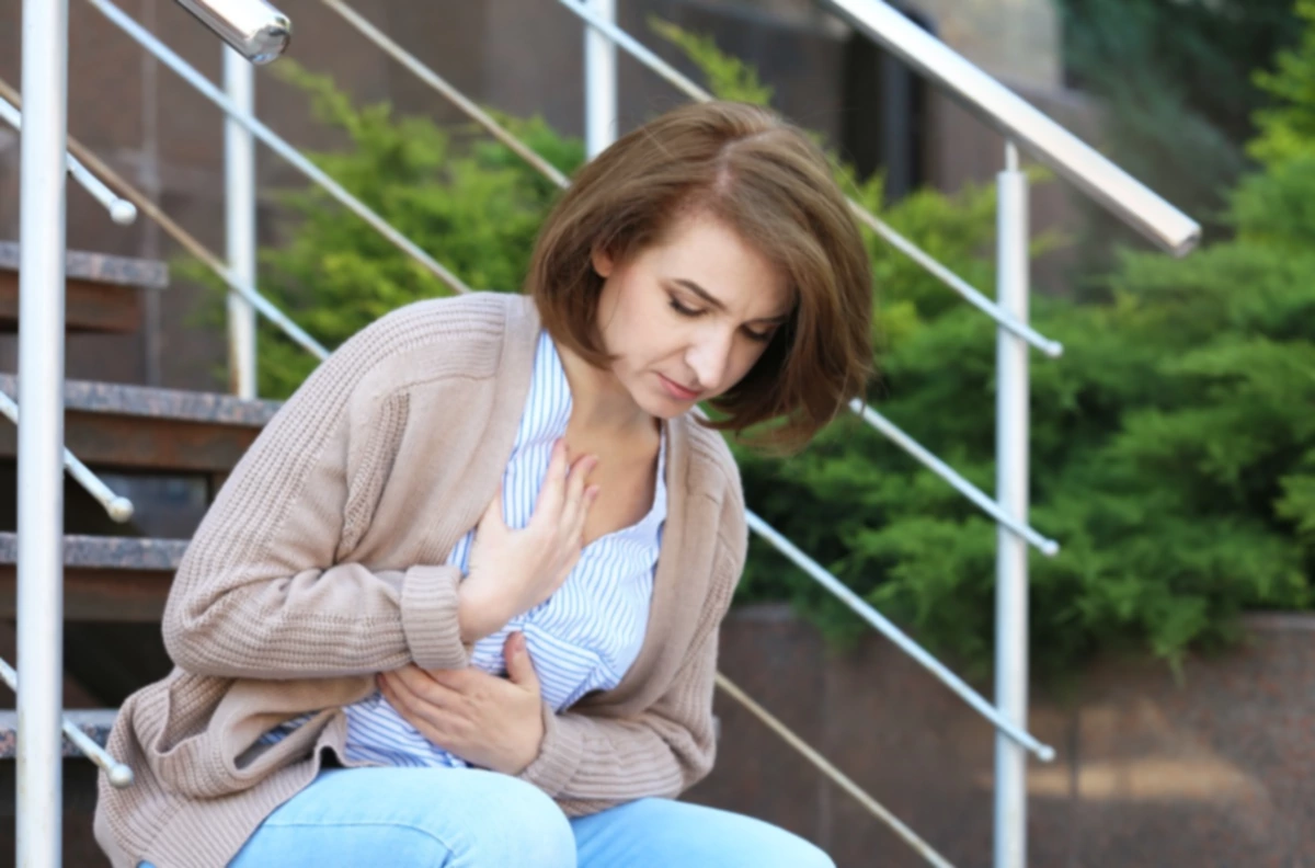 Mujer madura sufriendo un infarto en las escaleras, al aire libre