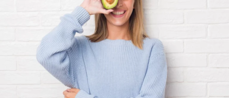 Beautiful,Young,Woman,Over,White,Brick,Wall,Eating,Fresh,Avocado